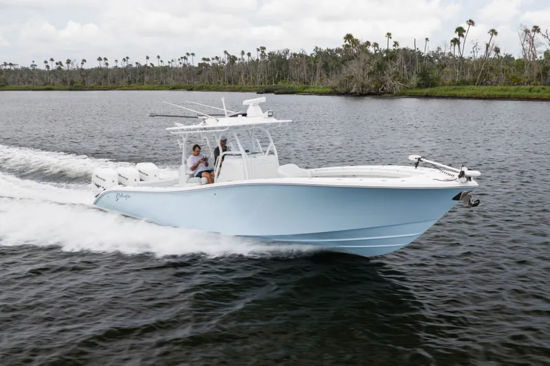 Slide: The Image of 2019 Yellowfin 36 Offshore boat cruising on a calm river with lush greenery. - 7