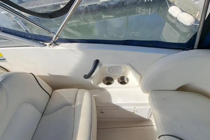 Slide: The Image of Interior of a 2007 Monterey 250 Cruiser boat with white seating and cup holders. - 17