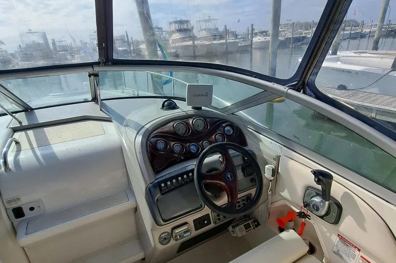 Slide: The Image of 2007 Monterey 250 Cruiser boat dashboard with steering wheel and controls, docked at marina. - 15