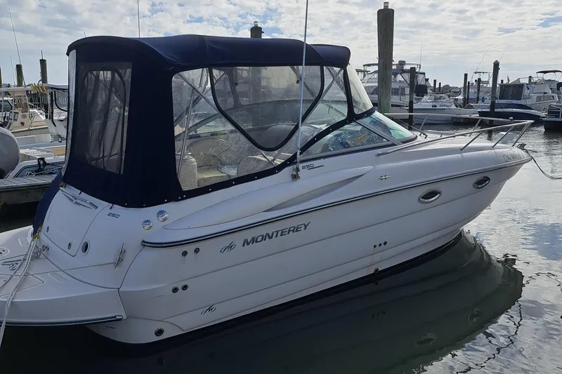 The Image of 2007 Monterey 250 Cruiser boat docked in marina, featuring blue canopy. - 3
