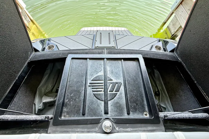 Slide: The Image of 2018 Malibu Wakesetter 21 MLX boat interior with storage compartment and lake view. - 33