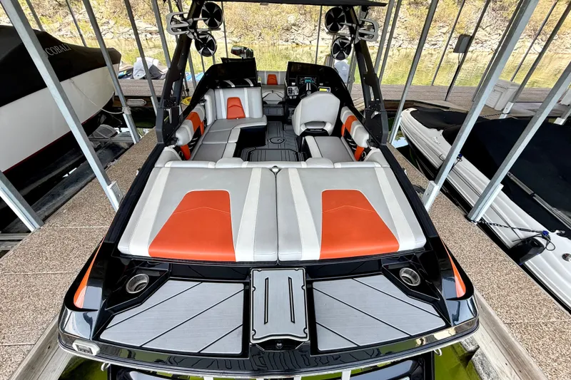 Slide: The Image of 2018 Malibu Wakesetter 21 MLX boat with orange and gray interior, docked in a marina. - 22