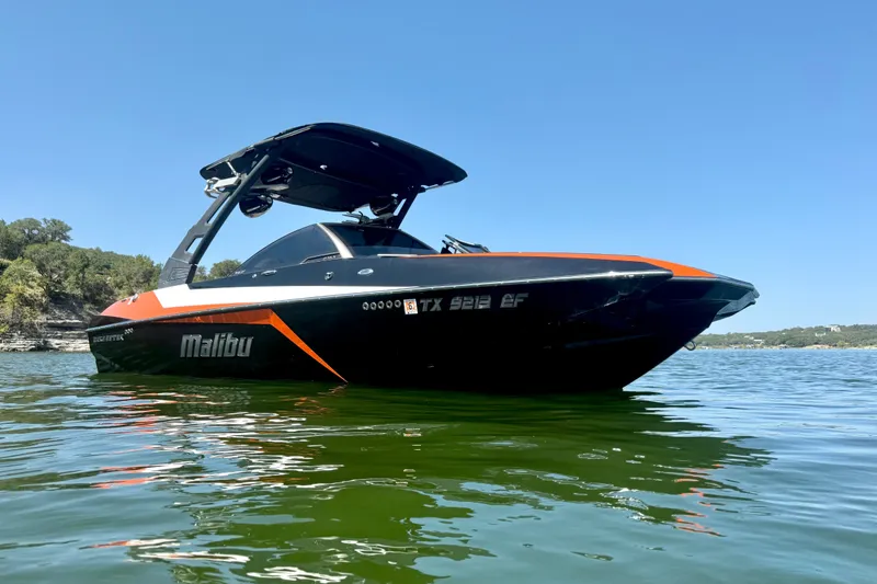 Slide: The Image of 2018 Malibu Wakesetter 21 MLX boat on calm lake under clear blue sky. - 8