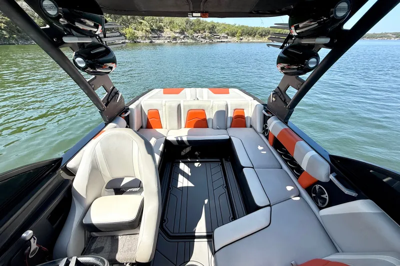 Slide: The Image of 2018 Malibu Wakesetter 21 MLX interior with stylish seating on a serene lake. - 26