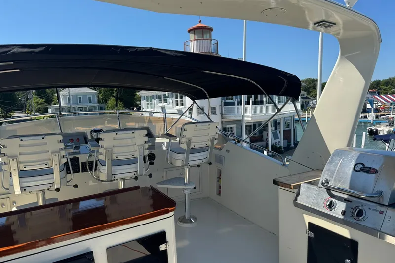 Slide: The Image of 1986 Hatteras 63 Cockpit Motor Yacht with covered helm and grill, docked near waterfront buildings. - 58