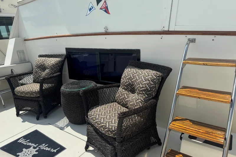 Slide: The Image of Outdoor seating area on 1986 Hatteras 63 Cockpit Motor Yacht with wicker chairs and welcome mat. - 8