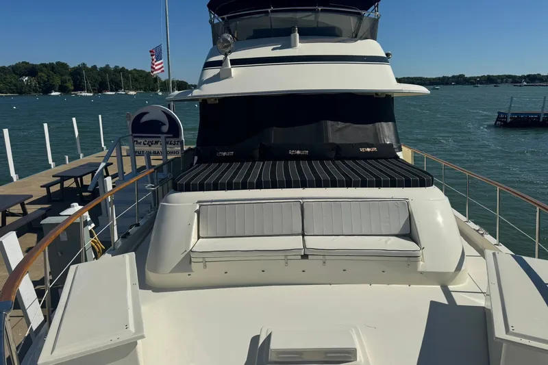 Slide: The Image of 1986 Hatteras 63 Cockpit Motor Yacht docked, featuring spacious deck and seating area. - 76