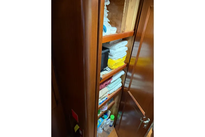 Slide: The Image of Storage cabinet with neatly stacked towels and cleaning supplies on a 1986 Hatteras 63 Cockpit Motor Yacht. - 38