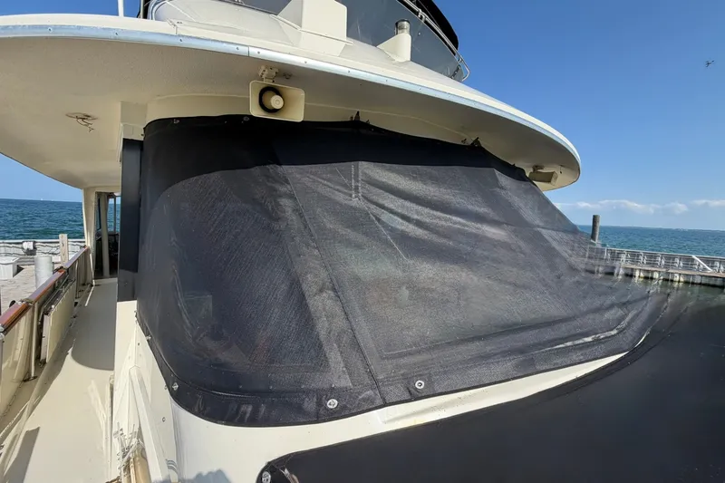 Slide: The Image of 1986 Hatteras 63 Cockpit Motor Yacht with covered windows docked by the sea. - 74
