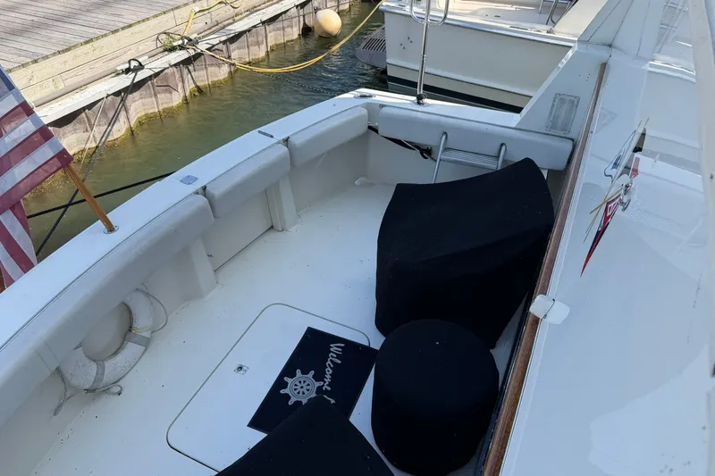 Slide: The Image of 1986 Hatteras 63 Cockpit Motor Yacht docked, featuring spacious seating and American flag. - 25