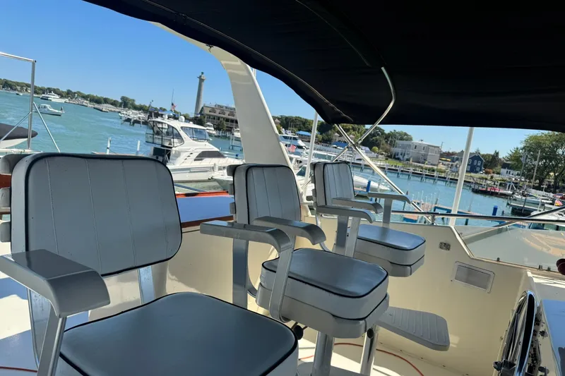 Slide: The Image of 1986 Hatteras 63 Cockpit Motor Yacht interior with seating, overlooking marina. - 63