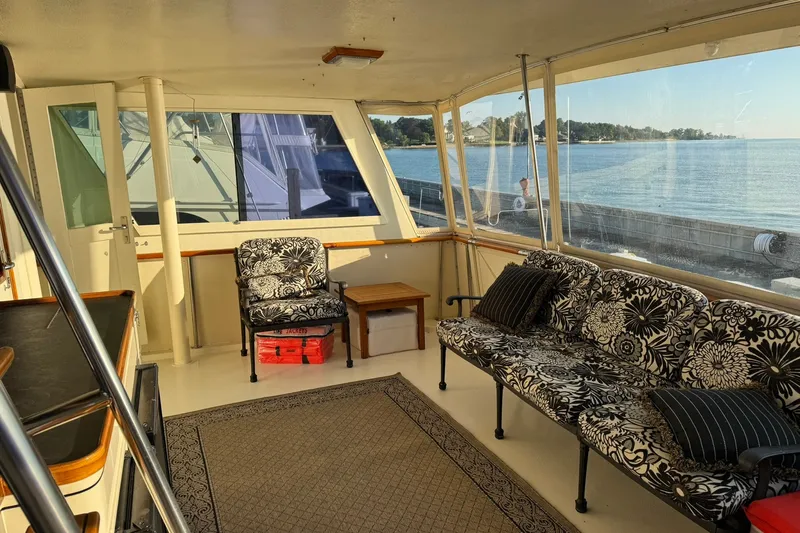 Slide: The Image of Interior of 1986 Hatteras 63 Cockpit Motor Yacht with floral seating and waterfront view. - 54