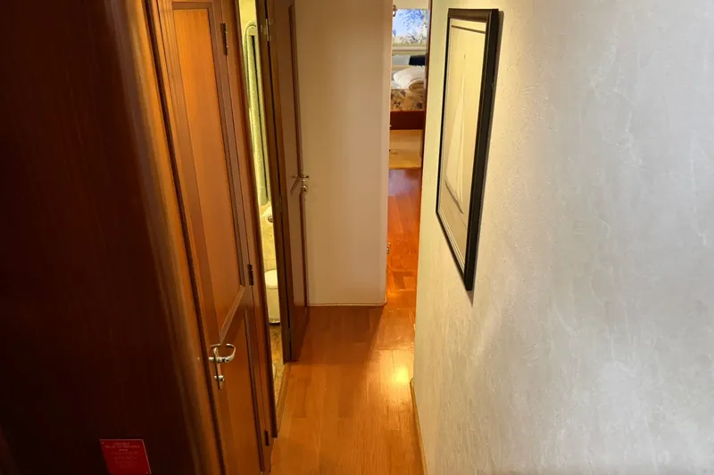 Slide: The Image of Interior hallway of 1986 Hatteras 63 Cockpit Motor Yacht with wooden flooring and framed artwork. - 36