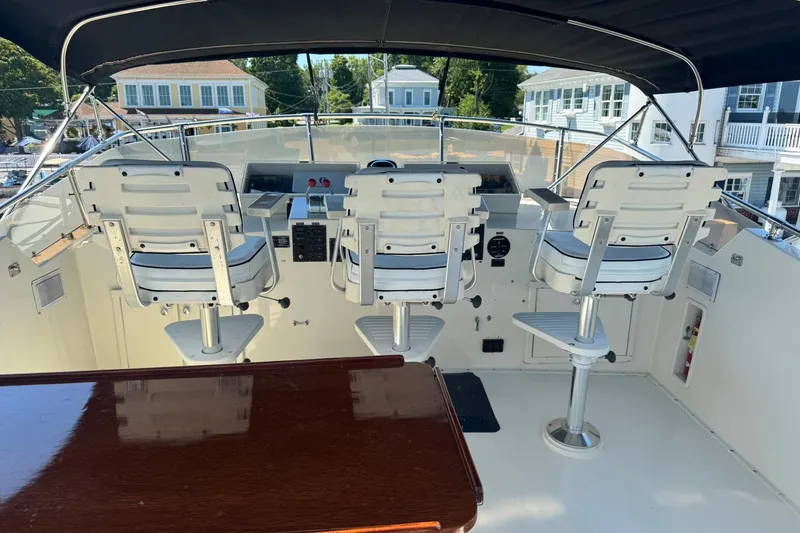 Slide: The Image of 1986 Hatteras 63 Cockpit Motor Yacht helm with three white captain chairs. - 57
