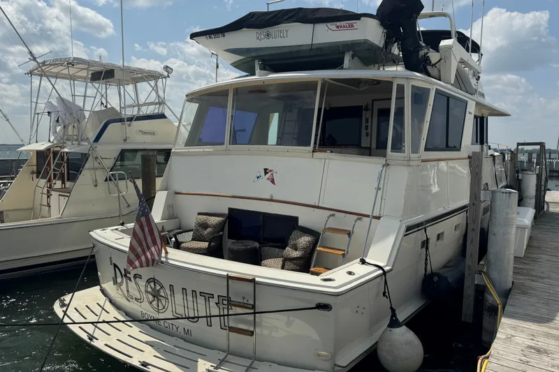 Slide: The Image of 1986 Hatteras 63 Cockpit Motor Yacht docked, featuring spacious deck and seating area. - 3