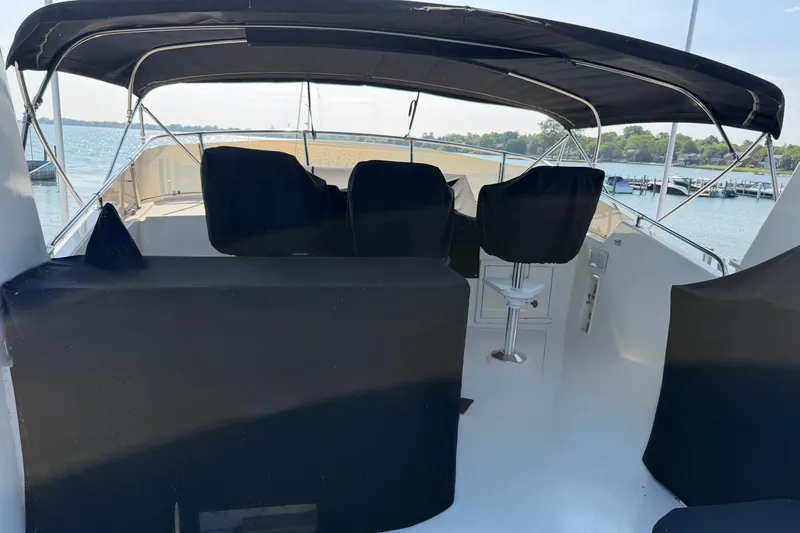 Slide: The Image of 1986 Hatteras 63 Cockpit Motor Yacht with covered seating on deck, overlooking serene waters. - 56