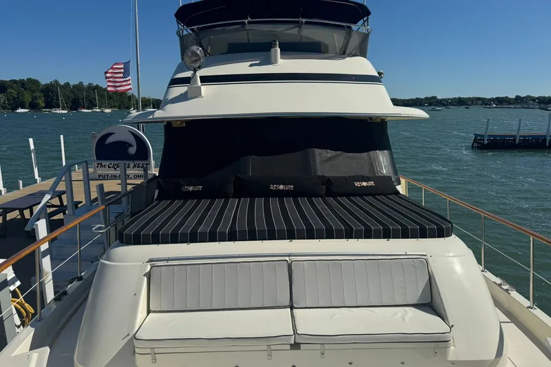 Slide: The Image of 1986 Hatteras 63 Cockpit Motor Yacht docked, featuring spacious deck and seating area. - 4