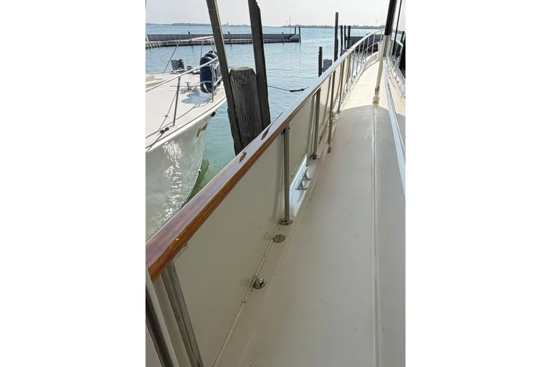 Slide: The Image of 1986 Hatteras 63 Cockpit Motor Yacht docked, showcasing sleek deck and railing design. - 5