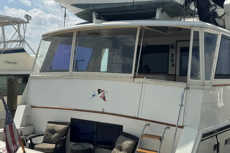 Slide: The Image of 1986 Hatteras 63 Cockpit Motor Yacht with outdoor seating and American flag. - 7