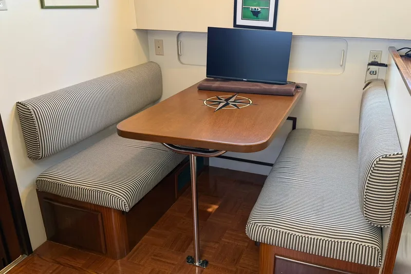 Slide: The Image of Dining area in 1986 Hatteras 63 Cockpit Motor Yacht with striped seating and wooden table. - 27