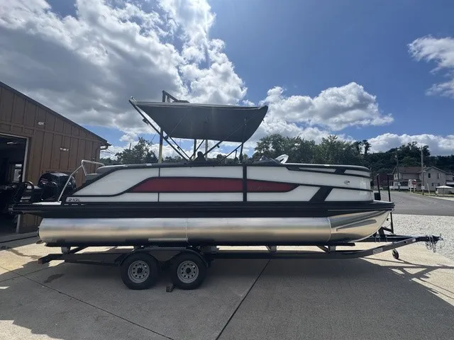 The Image of A modern pontoon boat with a black and red design, on a trailer under a sunny sky. - 1