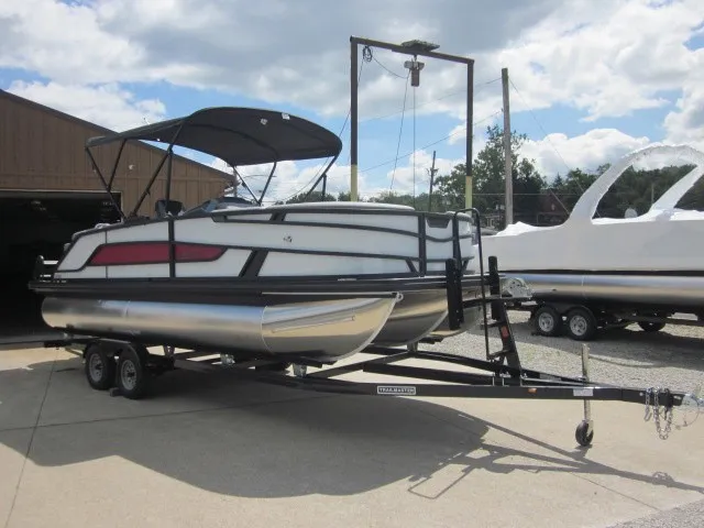 Slide: The Image of A modern pontoon boat with a black canopy and red accents sits on a trailer. - 7