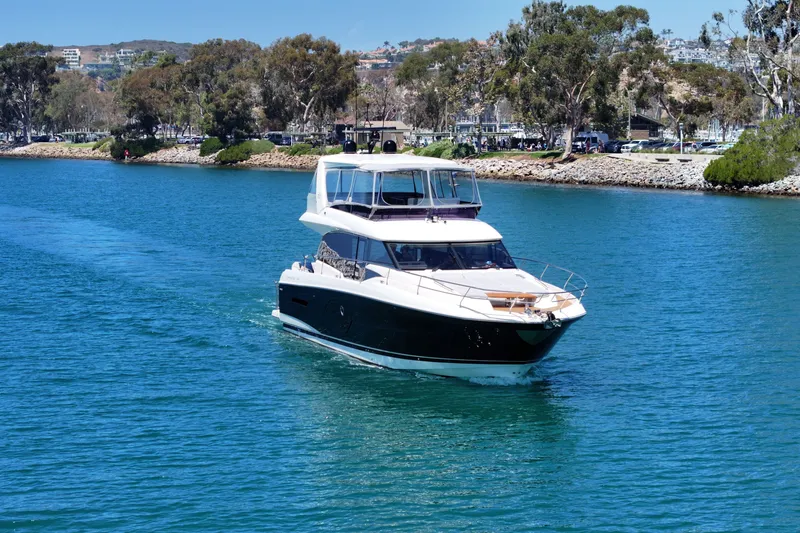 Slide: The Image of Luxury 2022 Prestige 590 yacht cruising on a serene blue waterway. - 3