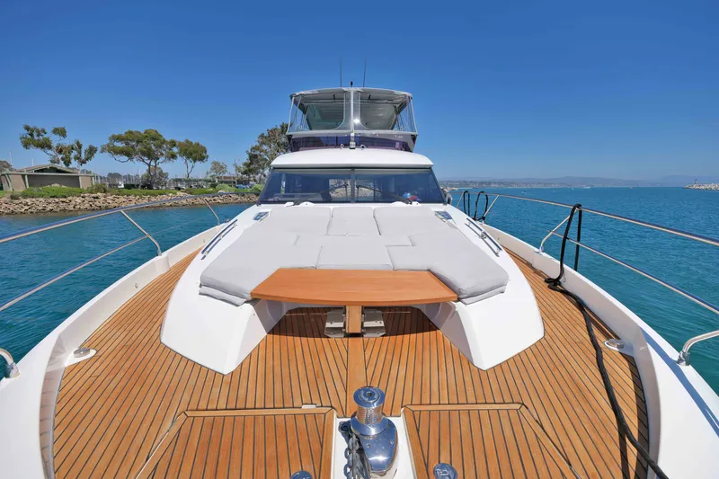 Slide: The Image of Luxury 2022 Prestige 590 yacht with spacious deck and sunbathing area on calm waters. - 16