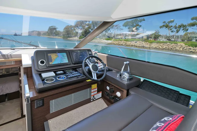 Slide: The Image of Interior view of 2022 Prestige 590 yacht cockpit with navigation controls and scenic waterway. - 42