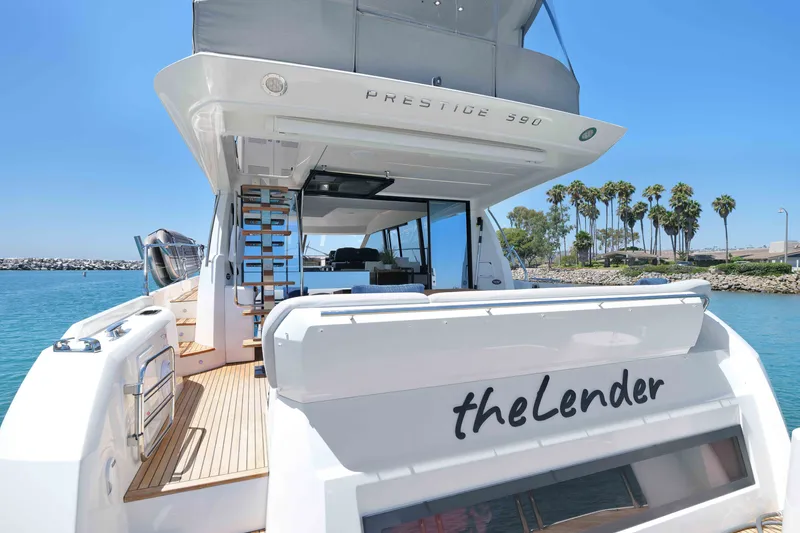 Slide: The Image of Luxury 2022 Prestige 590 yacht docked by palm trees, featuring sleek design and spacious deck. - 25