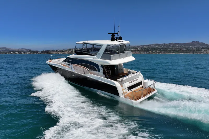 Slide: The Image of Luxury 2022 Prestige 590 yacht cruising on open sea with scenic coastline backdrop. - 10