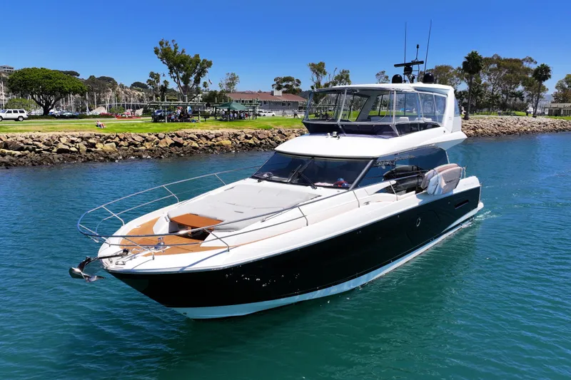 Slide: The Image of Luxury 2022 Prestige 590 yacht cruising in clear blue water near a scenic shoreline. - 4
