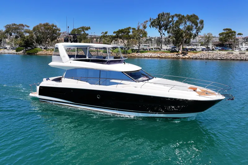 The Image of Luxury 2022 Prestige 590 yacht cruising on clear blue water near a scenic shoreline. - 0