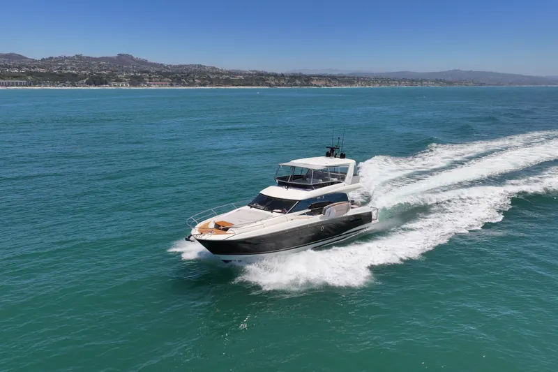 Slide: The Image of Luxury 2022 Prestige 590 yacht cruising on open sea under clear blue sky. - 13