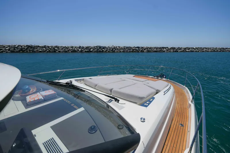 Slide: The Image of Prestige 590 yacht, 2022 model, cruising on clear blue waters near rocky shoreline. - 15