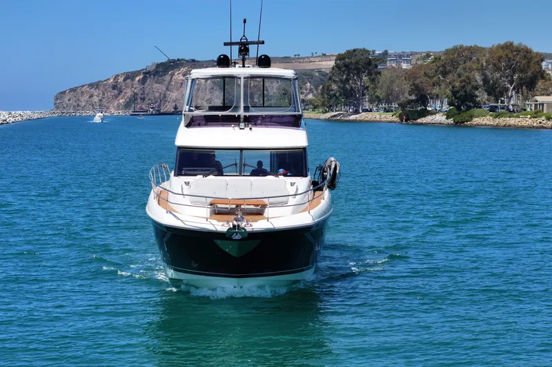 Slide: The Image of Front view of a 2022 Prestige 590 yacht cruising in a scenic coastal area. - 2