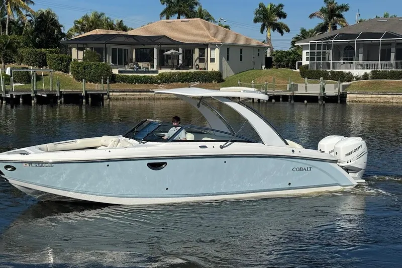Slide: The Image of 2018 Cobalt 30SC boat cruising on a sunny waterfront with houses in the background. - 12