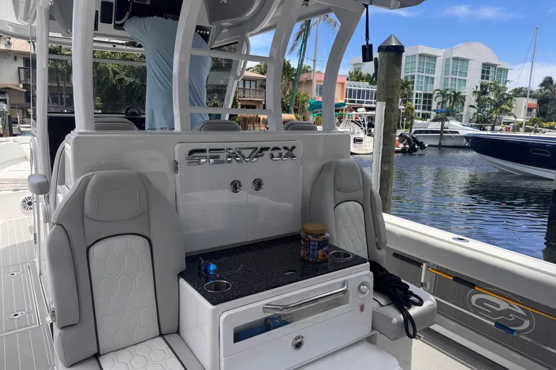 Slide: The Image of 2023 Sea Fox 368 Commander boat interior with seating and console, docked by waterfront homes. - 33