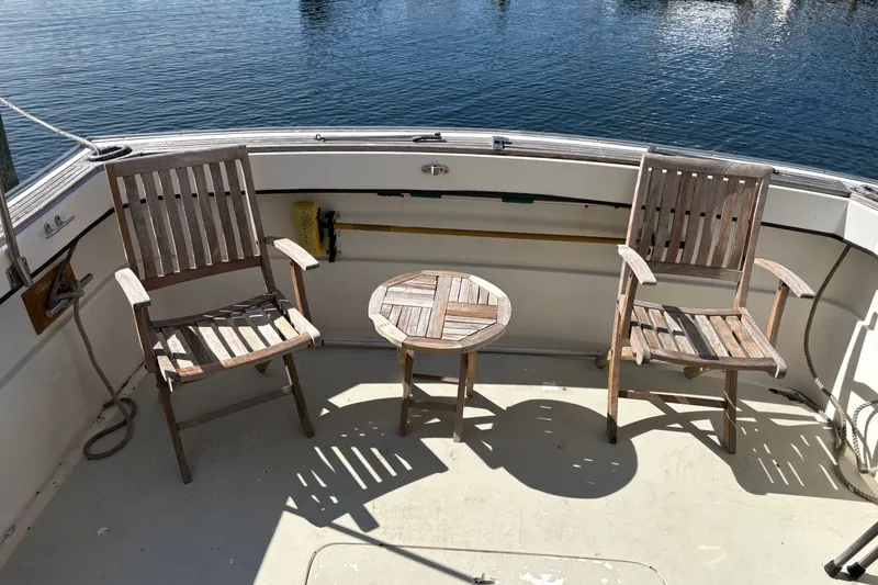 Slide: The Image of Wooden chairs and table on 1978 Mainship 34 Trawler deck by the water. - 9