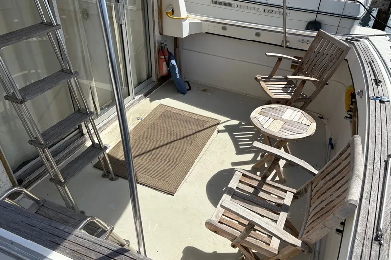 Slide: The Image of 1978 Mainship 34 Trawler deck with wooden chairs and table, ladder, and safety equipment. - 8