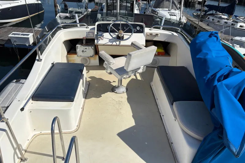 Slide: The Image of 1978 Mainship 34 Trawler cockpit with seating, steering wheel, and marina view. - 12