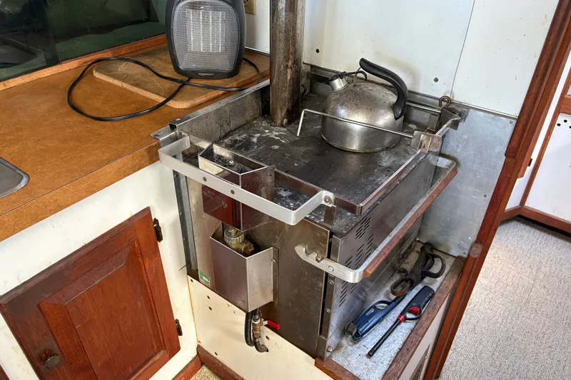 Slide: The Image of 1978 Mainship 34 Trawler galley with stove, kettle, and heater on wooden countertop. - 25