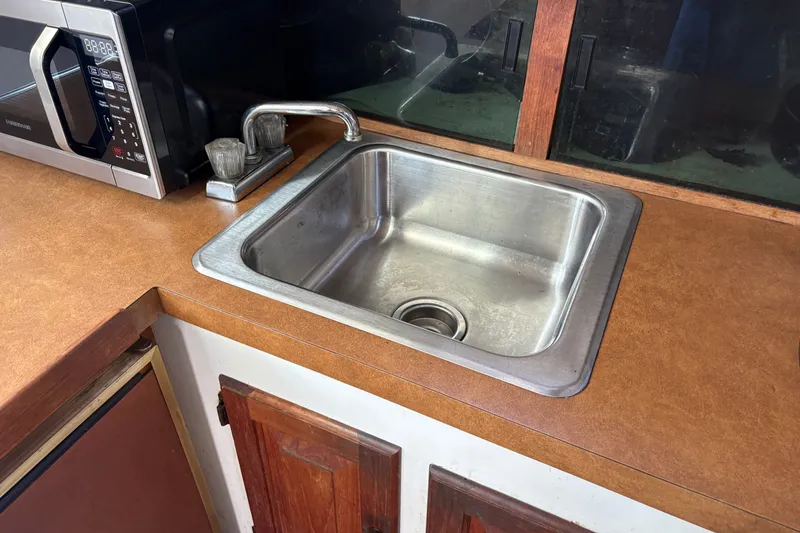 Slide: The Image of 1978 Mainship 34 Trawler kitchen sink with microwave and wooden cabinets. - 26