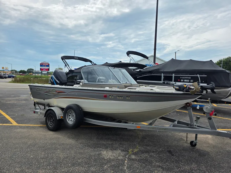 The Image of A 2004 Crestliner 1850 Sportfish on a trailer, parked in a lot under a cloudy sky. - 0