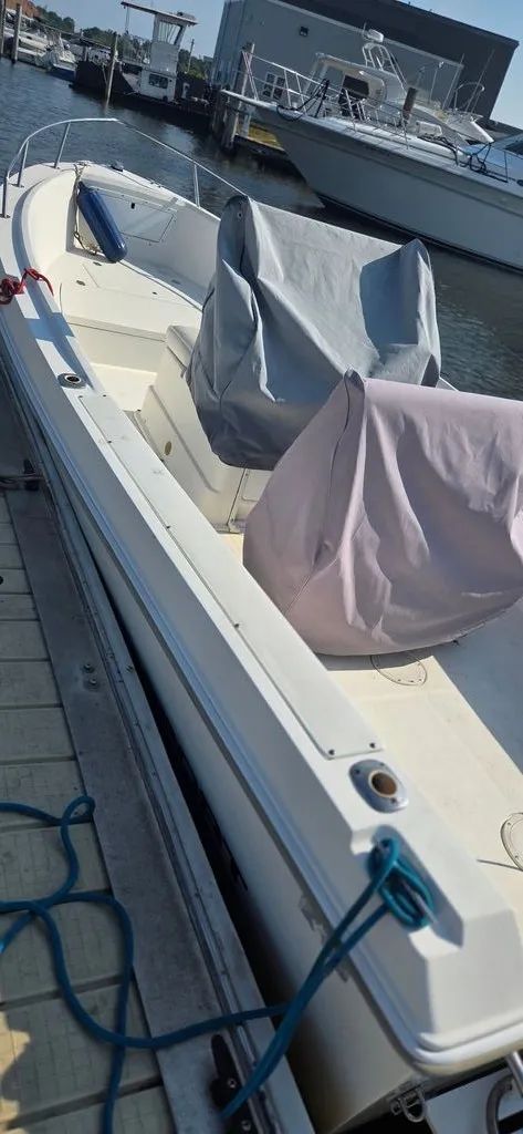 Slide: The Image of A 1999 Aquasport 200 Osprey docked. The seats are covered for protection. - 6