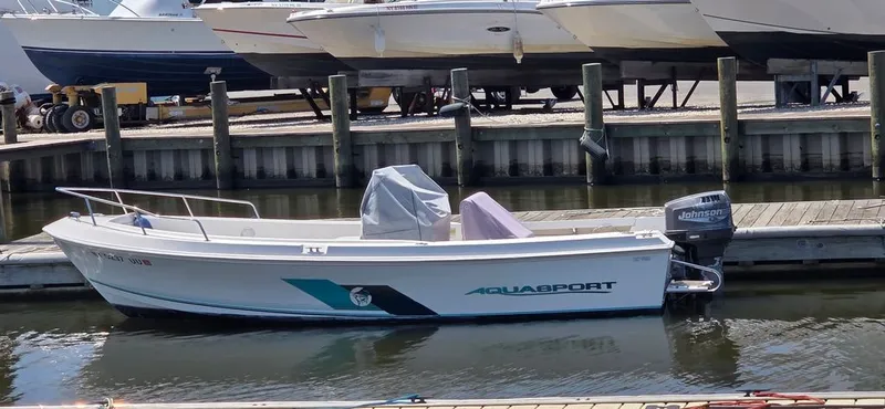 Slide: The Image of A 1999 Aquasport 200 Osprey is docked in the water. It features a Johnson outboard motor. - 2
