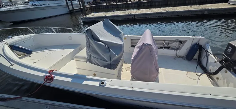 Slide: The Image of A 1999 Aquasport 200 Osprey docked. The seats are covered for protection. - 4