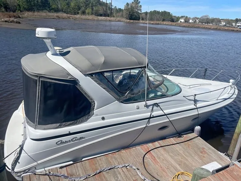 The Image of A 2000 Chris-Craft 328 Express Cruiser docked at a wooden pier in calm waters. - 0