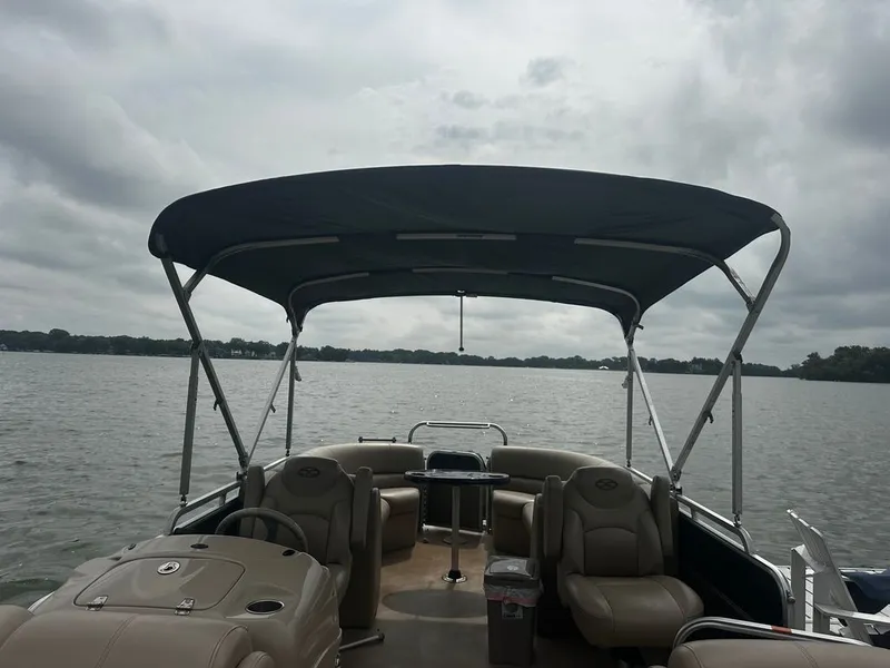 Slide: The Image of A pontoon boat with a blue canopy, comfortable seating, and a helm on a calm lake. - 3