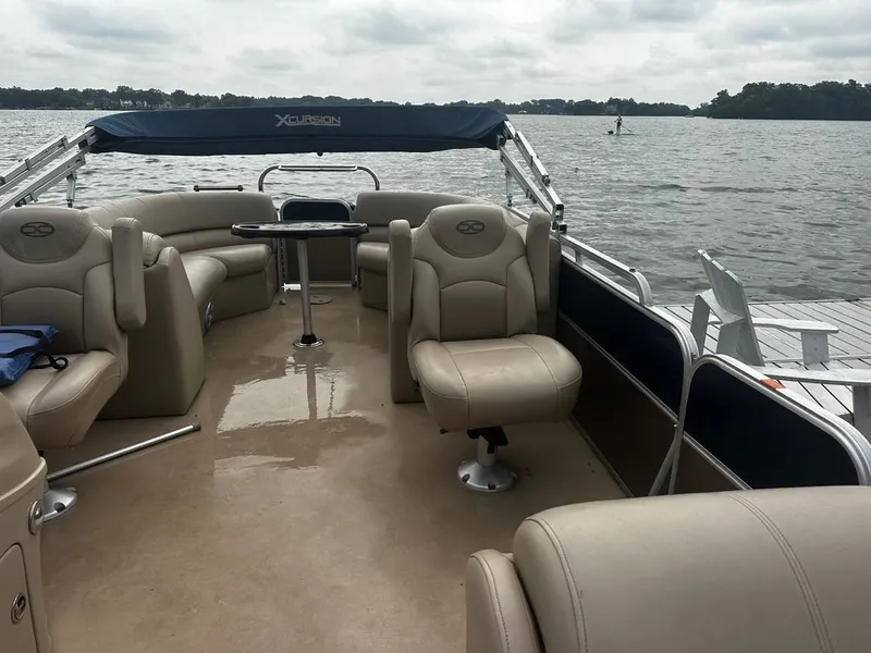 Slide: The Image of A 2013 Xcursion 23RF pontoon boat with beige seating and a blue canopy on a lake. - 9